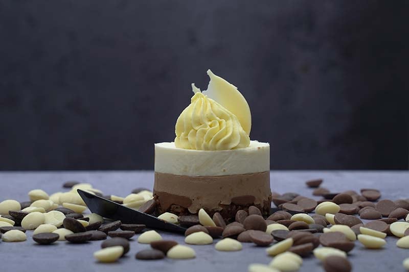 A dessert of white, milk and dark chocolate, ringed with chocolate buttons