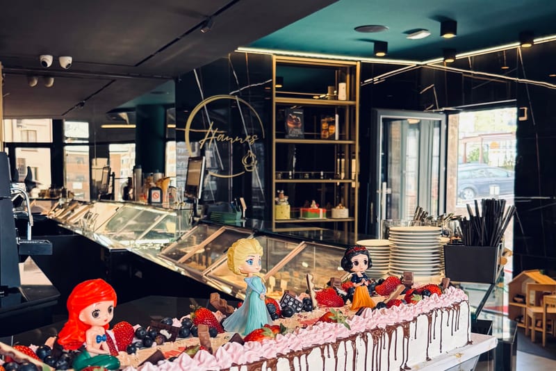 Inside the Hannes patisserie — the dessert cabinets, the gold Hannes sign and a long celebration cake on the counter